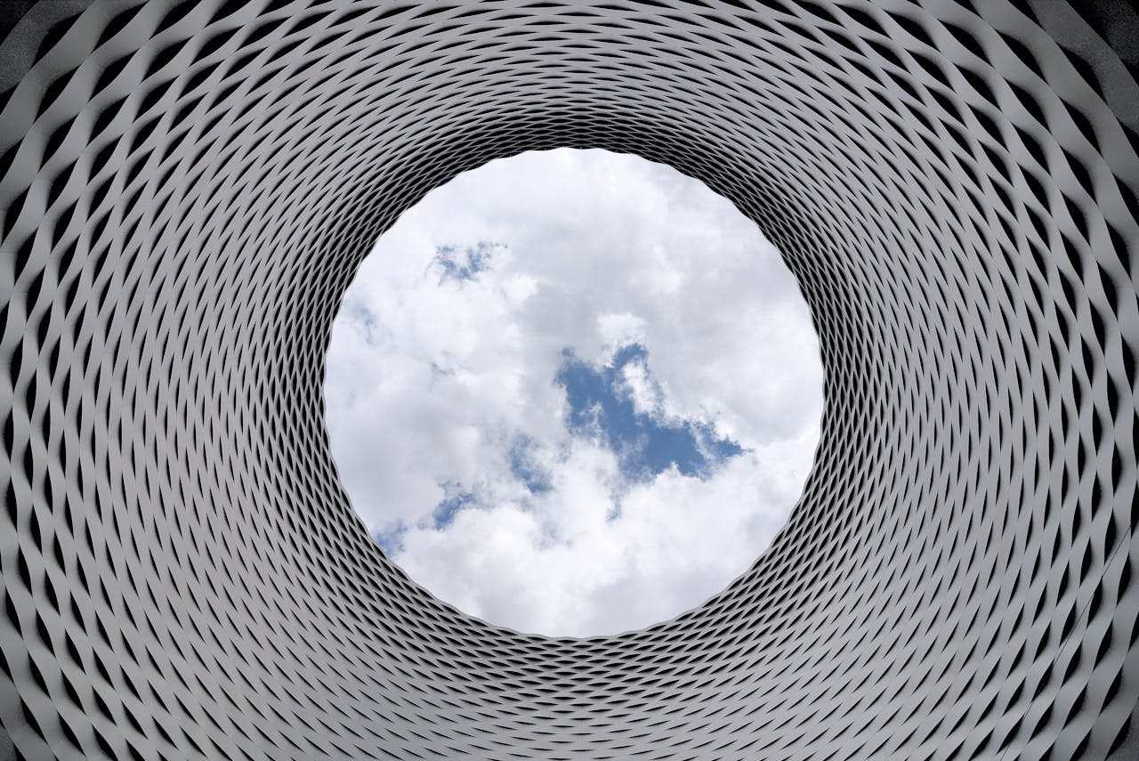 Modern architectural tunnel with a geometric pattern revealing a bright sky.